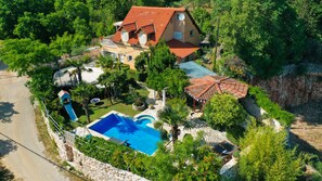 Ein Haus mit Schwimmbad, umgeben von üppiger Vegetation und einer felsigen Landschaft.