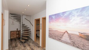 Un escalier avec des éléments en bois, une porte en bois et un tableau représentant une scène de plage.