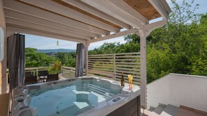 Ein Whirlpool unter einer Pergola mit Blick auf Grünflächen und Berge.