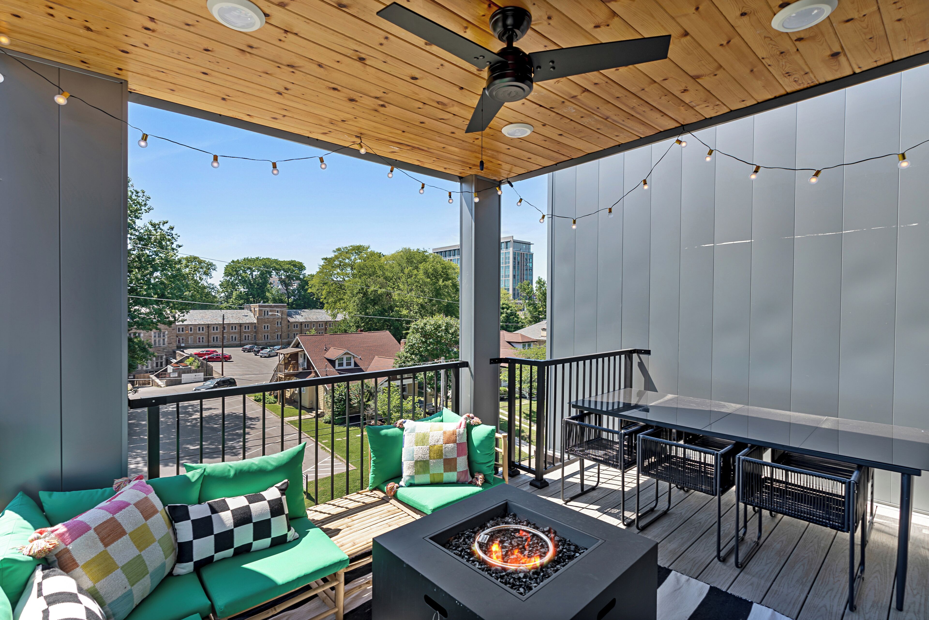 A covered outdoor deck with a fire pit, seating area, and a table.