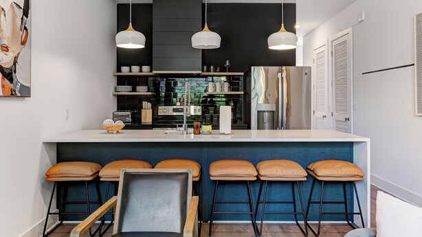 A modern kitchen with a central island, bar stools, and pendant lighting. - The Grove (Nashville)