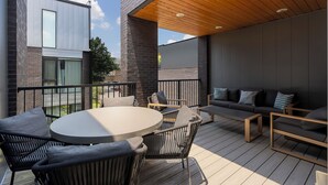 A modern outdoor deck with a round table, chairs, and a sofa. - The Grove (Nashville)