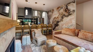 A modern living room with a sofa, chairs, a coffee table, and a kitchen area in the background. - The Grove (Nashville)