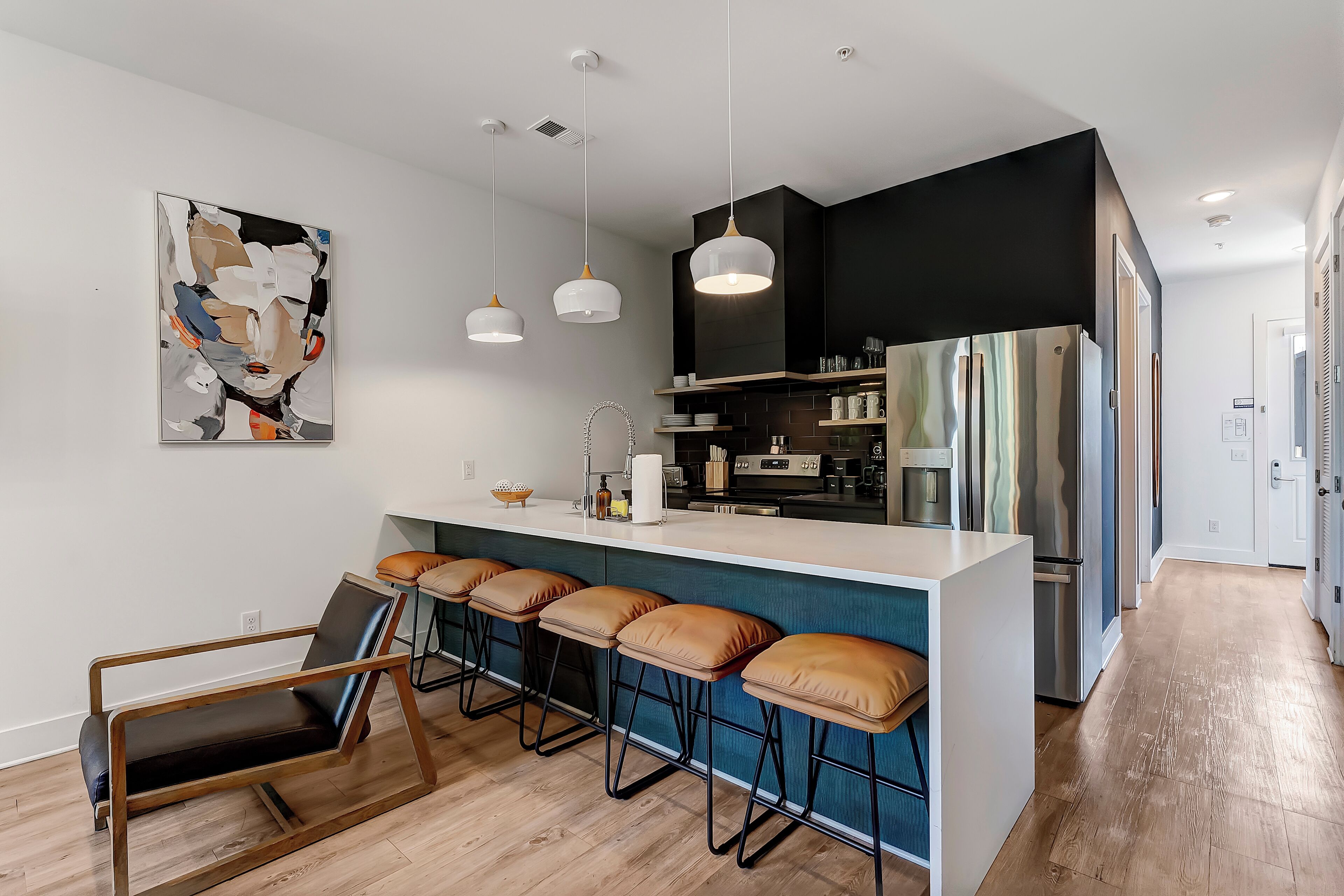 A modern kitchen with a bar area, bar stools, and a dining table with chairs.