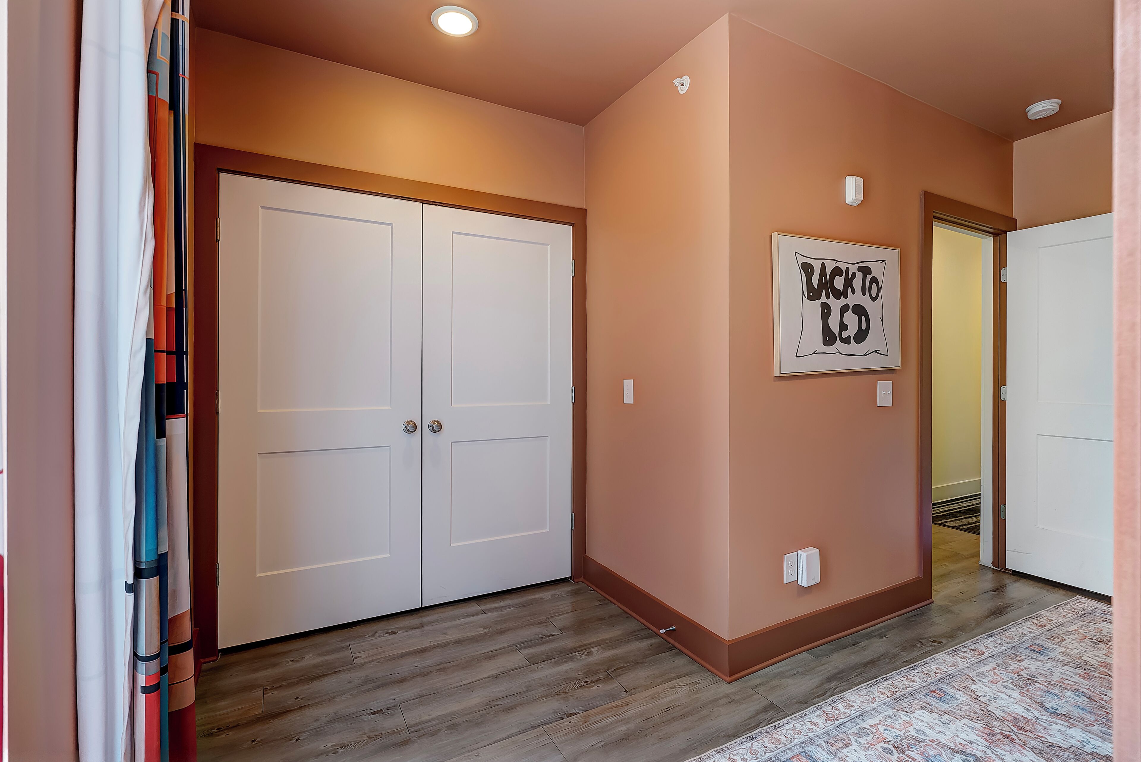A hallway with double doors, a 'Back to Bed' sign, and a patterned rug.