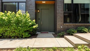 A modern building with a green door, a brick facade, and a well-maintained garden. - The Grove (Nashville)