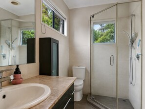 Un baño moderno con lavamanos, inodoro y ducha con mampara de vidrio.
