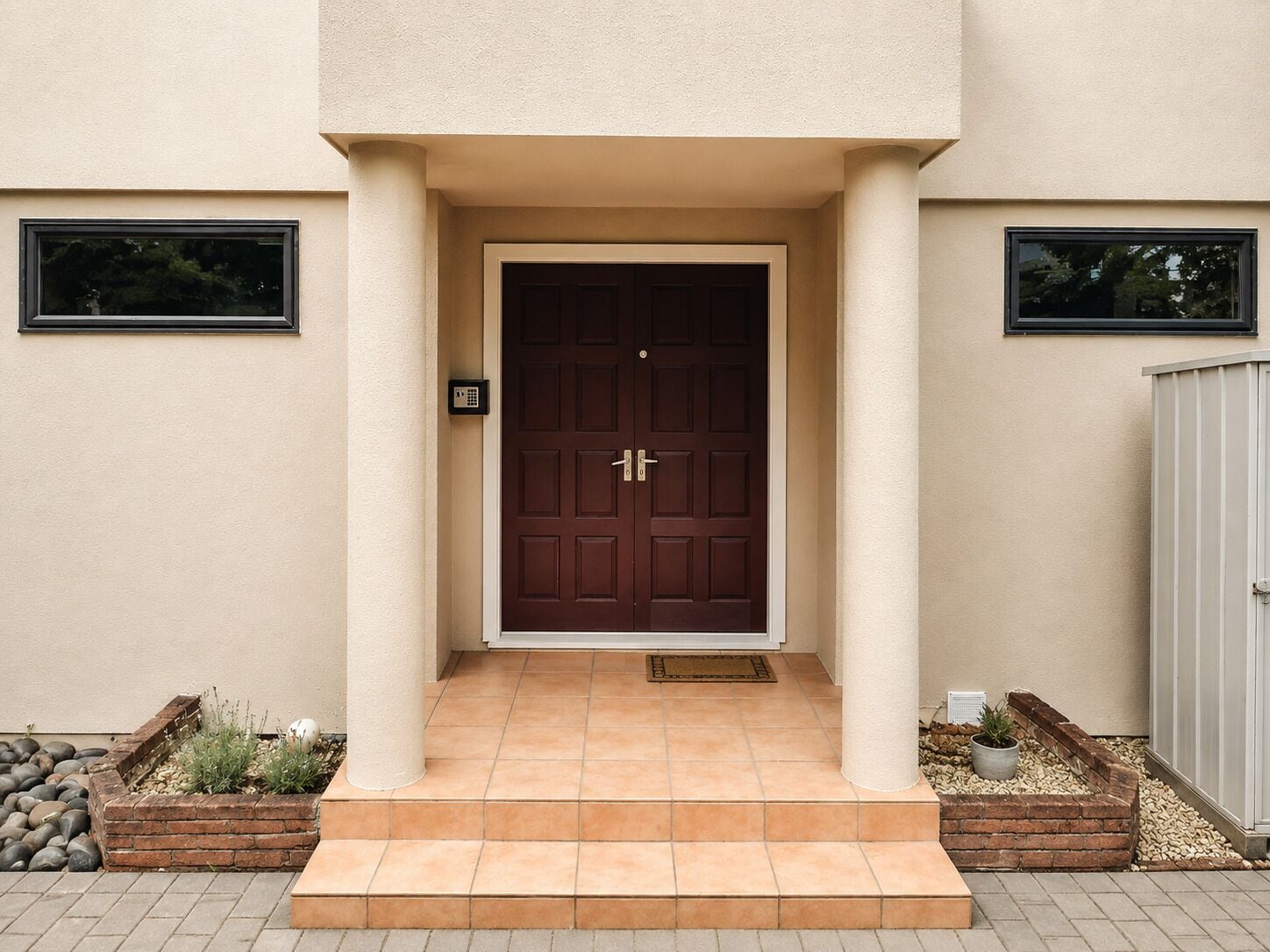 A house entrance with a brown door, a small porch, and two windows.