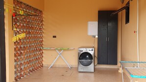 Un área de lavandería con lavadora, tendedero y un tendedero de pared.