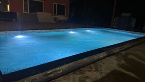 Ein rechteckiger Swimmingpool mit einer gefliesten Kante und einer ihn umgebenden Holzterrasse.