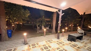 Ein Terrassenbereich im Freien mit gemustertem Boden, einer Sitzgruppe und dekorativer Beleuchtung.
