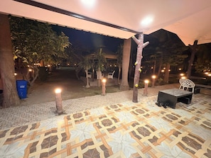Un patio al aire libre con suelo estampado, una zona de estar e iluminación decorativa.