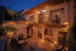 A two-story building with a balcony, outdoor seating area, and a sign indicating a business. - Alley Stone House Cappadocia (Nevsehir)