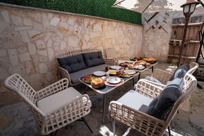 Un área de comedor al aire libre con mobiliario de mimbre y paredes de piedra.