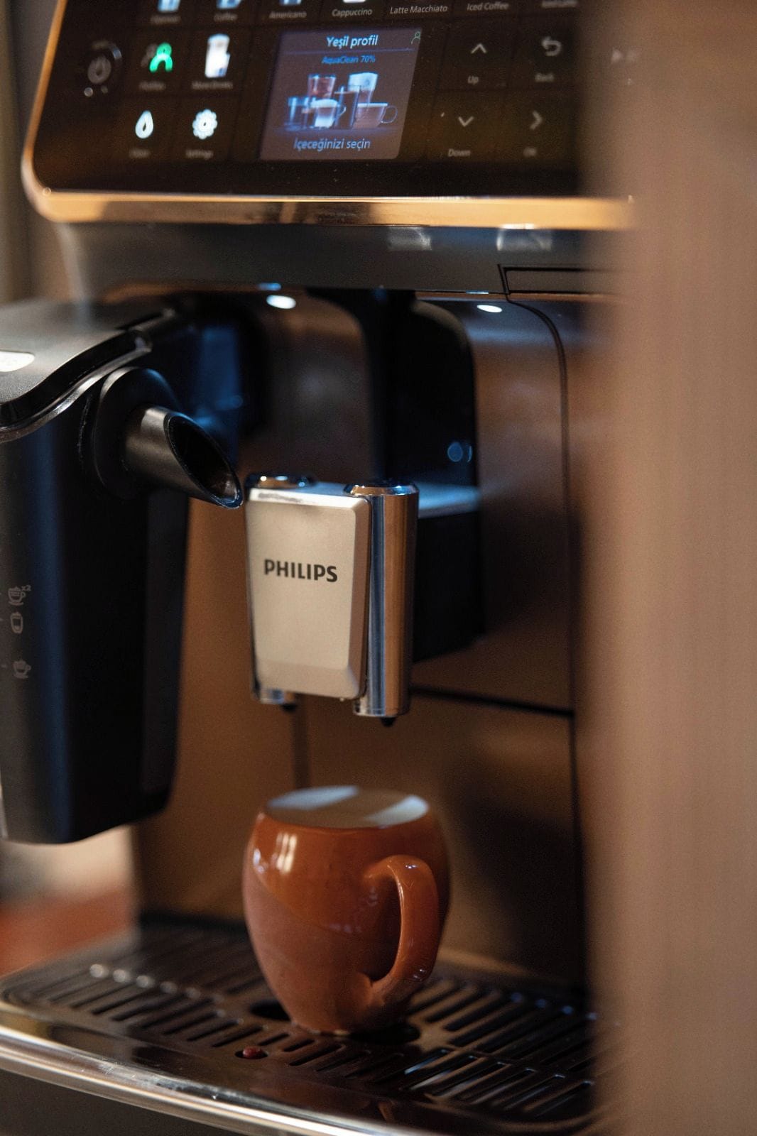 Een koffieapparaat met een digitaal scherm en een beker met logo.