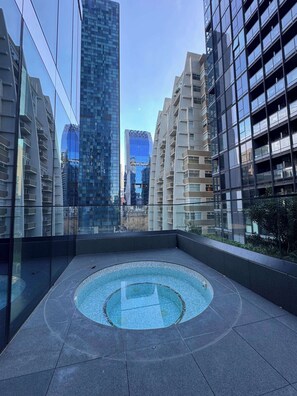 Ein Pool auf dem Dach mit kreisförmigem Design, umgeben von modernen Gebäuden mit reflektierenden Glasfassaden.