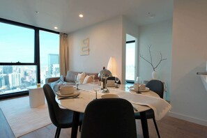 Ein stilvolles Esszimmer mit einem runden Tisch, Stühlen und Blick auf die Stadt durch große Fenster.