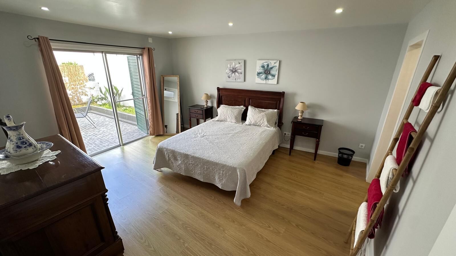 A bedroom with a bed, a dresser, a mirror, and a window with curtains.