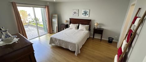 A bedroom with a bed, a dresser, a mirror, and a window with curtains.