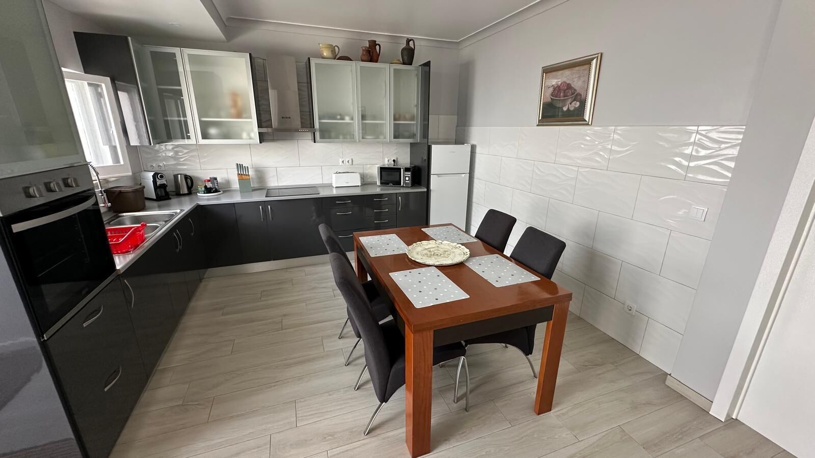 Une cuisine moderne avec une table à manger, des meubles noirs et un dosseret de carrelage blanc.