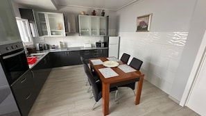 A modern kitchen with a dining table, black cabinets, and a white tiled backsplash.
