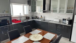 Eine moderne Küche mit dunklen Schränken, einem Holztisch und einem eingebauten Backofen.