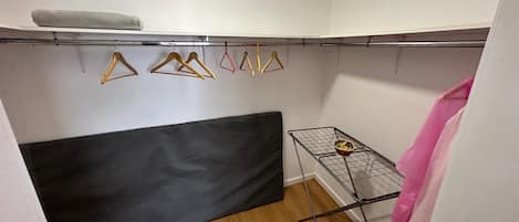 A small room with a black sofa, a metal drying rack with clothes, and a white wall.
