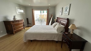 Een slaapkamer met een bed, een dressoir, een lamp en uitzicht.