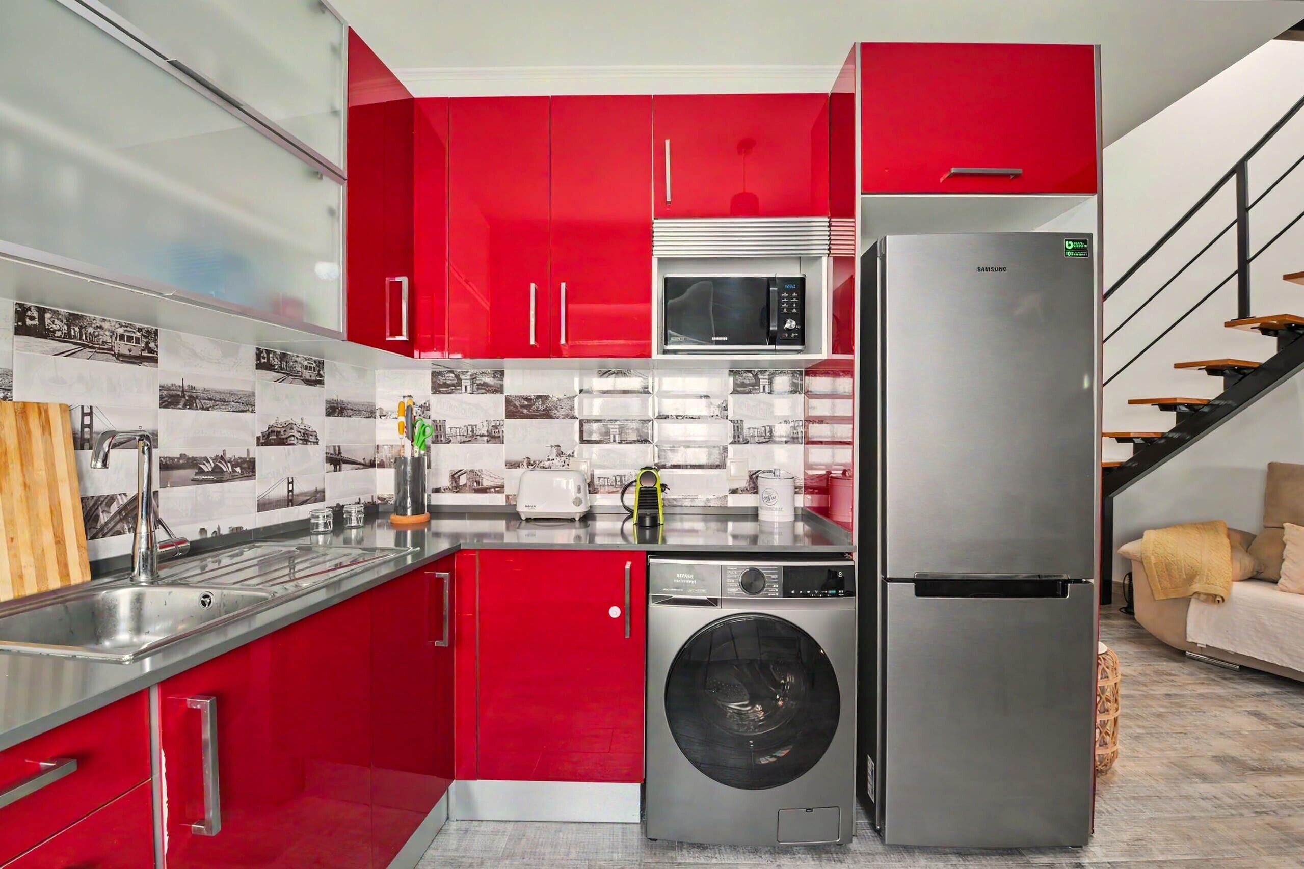 A modern kitchen with red cabinetry, stainless steel appliances, and a tiled backsplash.