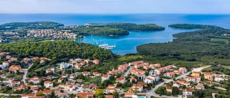 A coastal town with residential buildings, a marina, and clear blue waters.