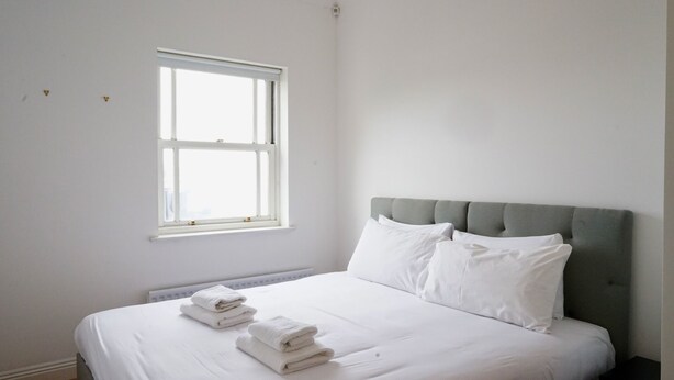Une chambre à coucher avec un lit, des oreillers, une fenêtre et des serviettes.