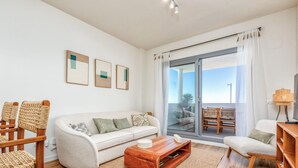 Uma sala de estar moderna com sofá, cadeiras, mesa de centro e uma varanda com vista.