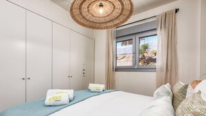 Quarto com cama, janela com vista, guarda-roupa e luminária suspensa.