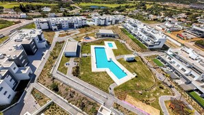 Um moderno complexo residencial com piscina central, vários edifícios e paisagismo bem cuidado.