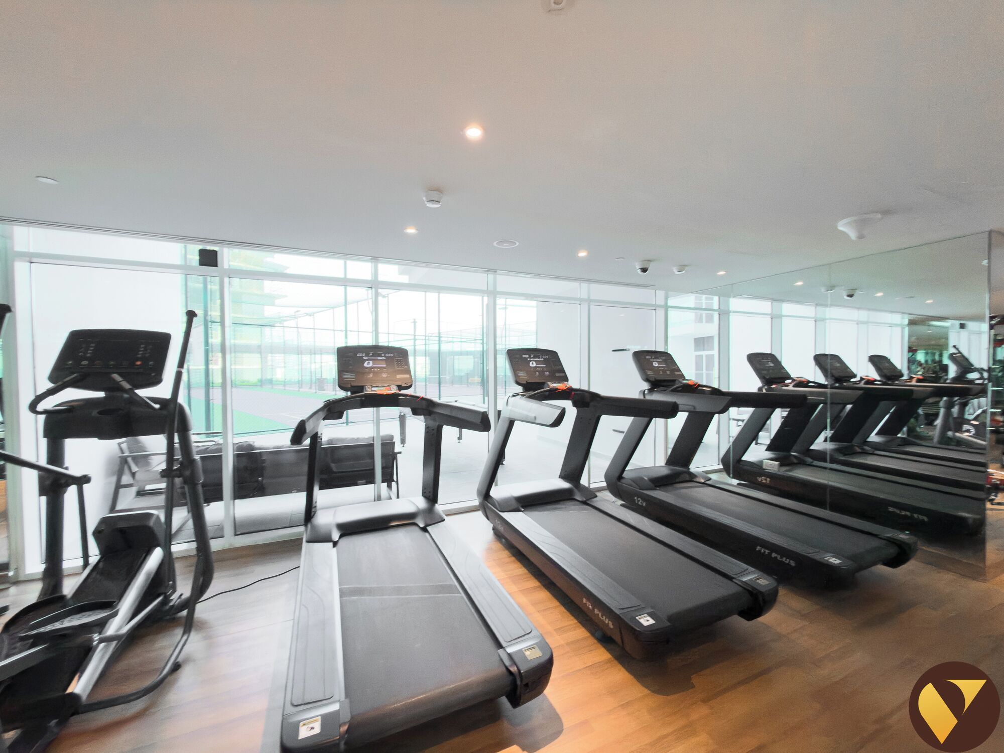 Een sportschool met meerdere loopbanden en hometrainers, grote ramen en een schoon, modern design.