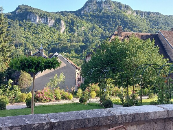 A stone wall, a garden with various plants, and a building with a sloped roof.