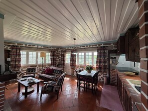 A spacious room with a stone wall, a wooden ceiling, and a dining area with a table and chairs. - Rustic Cottage with 2 Rooms in Estorãos, Ponte de Lima (Estorãos)