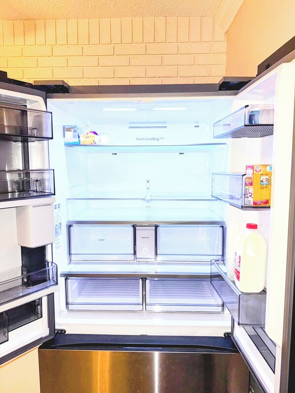 A refrigerator with a water filter compartment, a milk carton, and a coffee maker.