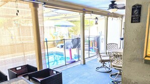 A covered patio area with outdoor furniture, a pool, and a ceiling fan.