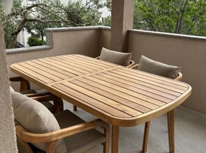 Ein Holztisch mit Stühlen und Kissen auf einem Balkon.