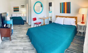 Una habitación de hotel con dos camas, un escritorio, una silla, un televisor y un espejo.