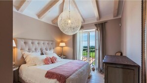 Une chambre avec un grand lit, un plafond en bois, un luminaire suspendu et une vue sur l’extérieur.