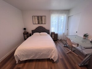 A bedroom with a bed, bedside tables, a desk, a chair, a potted plant, and a painting on the wall. - Master Suite with Private Bath & Shared Space in welcoming Portland (Portland)