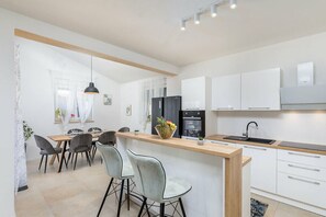 Eine moderne Küche mit weißen Schränken, einem schwarzen Kühlschrank und einer Holzeile mit Barhocker.