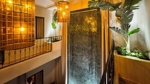 A modern interior with a curved ceiling light, a herringbone-patterned wall, and a large plant. - riadnumero19 (Marrakech)