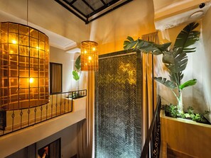 A modern interior with a curved ceiling light, a herringbone-patterned wall, and a large plant. - riadnumero19 (Marrakech)
