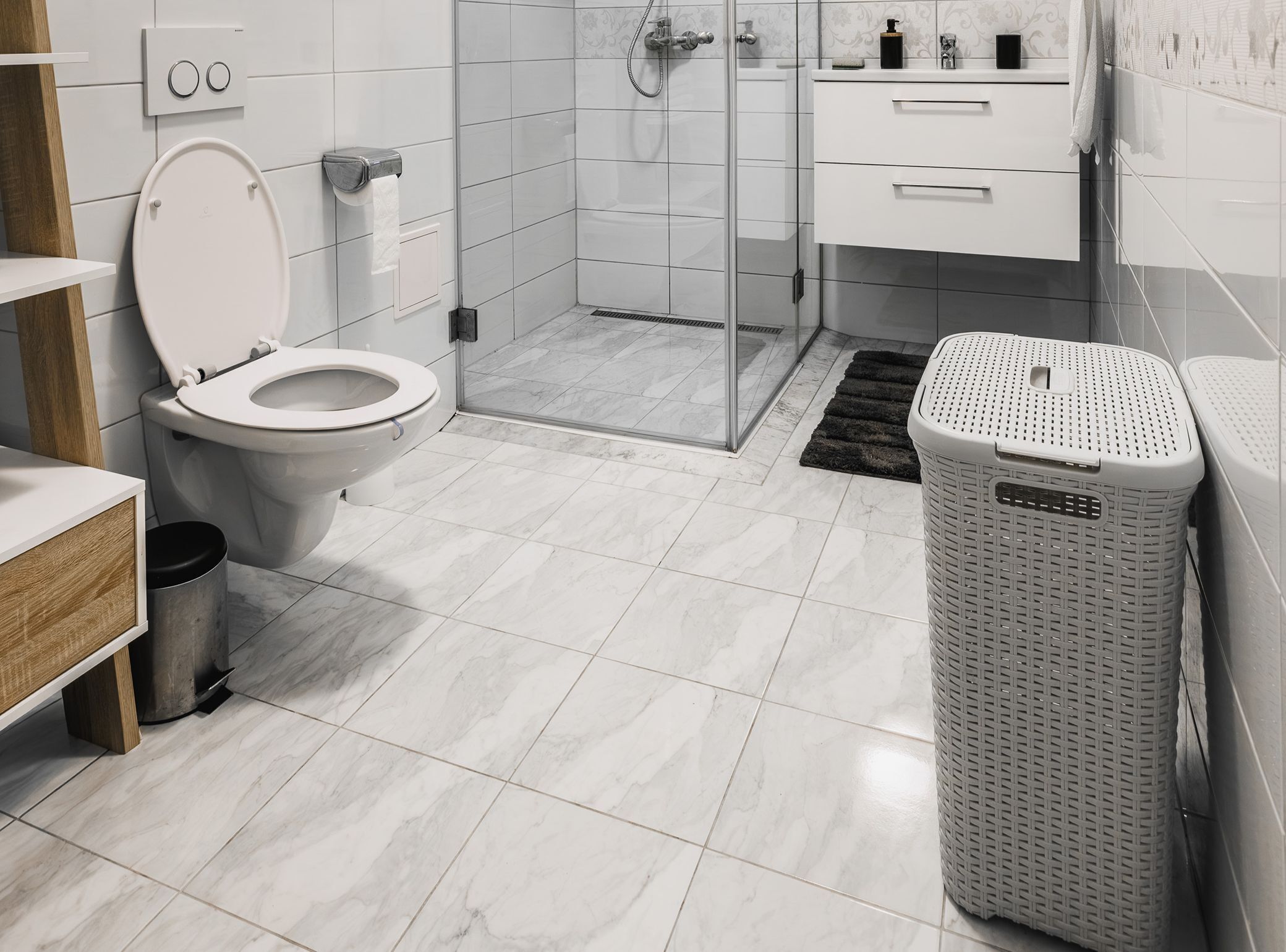 Ein modernes Badezimmer mit Toilette, Dusche und Wäschekorb.