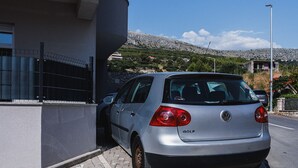 Hopeanvärinen Volkswagen Golf -auto oli pysäköitynä rakennuksen eteen. Rakennuksessa oli kivijulkisivu ja metalliaita.
