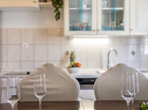 A kitchen with white cabinets, a sink, and a countertop with a bowl of fruit. - Villa Pax (Lovreć)