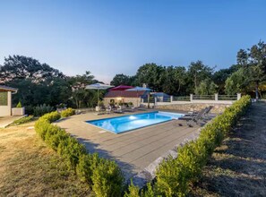 A rectangular swimming pool with a stone deck, surrounded by greenery and a covered seating area. - Villa Pax (Lovreć)